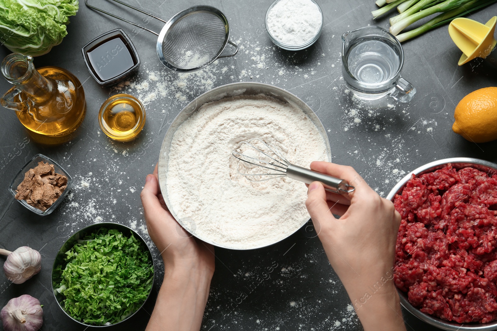 Photo of Woman cooking delicious gyoza at black table, top view