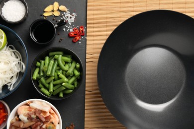 Flat lay composition with black wok, spices and products on dark textured table