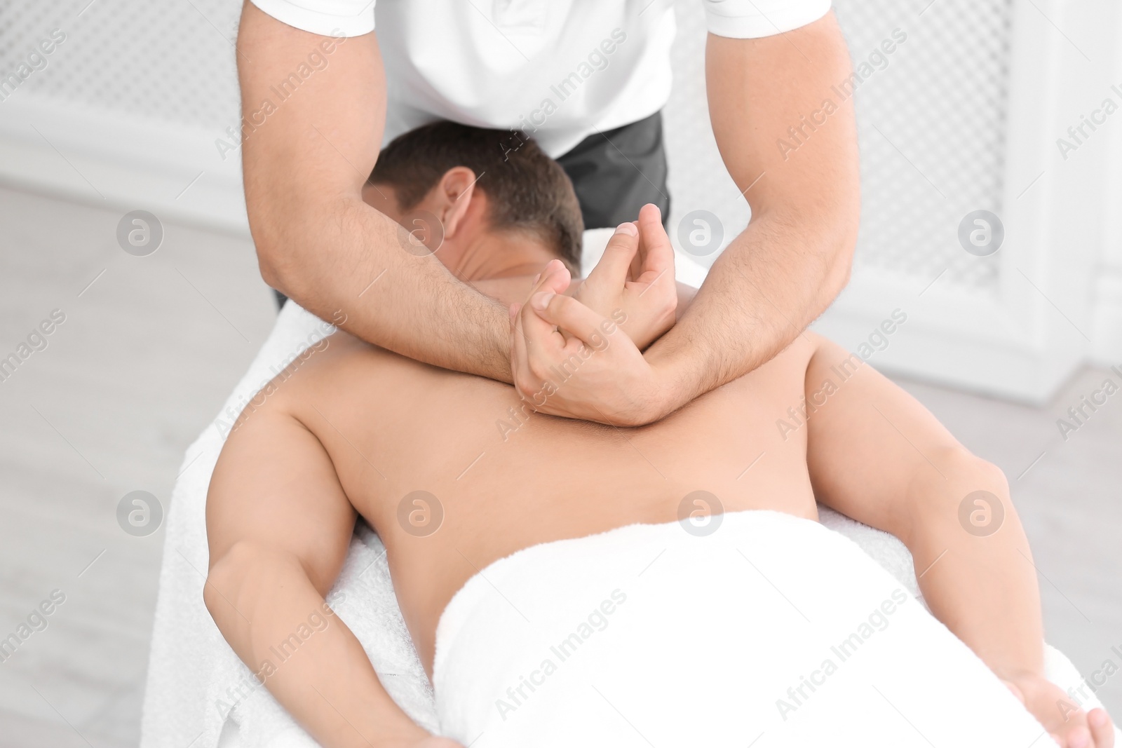 Photo of Relaxed man receiving back massage in wellness center