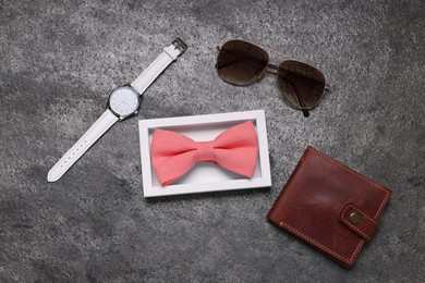 Photo of Stylish coral bow tie, sunglasses, wallet and wristwatch on grey textured background, flat lay