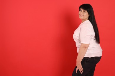 Photo of Beautiful overweight mature woman with charming smile on red background. Space for text