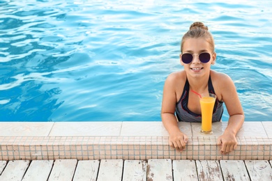 Photo of Happy little girl with drink in swimming pool