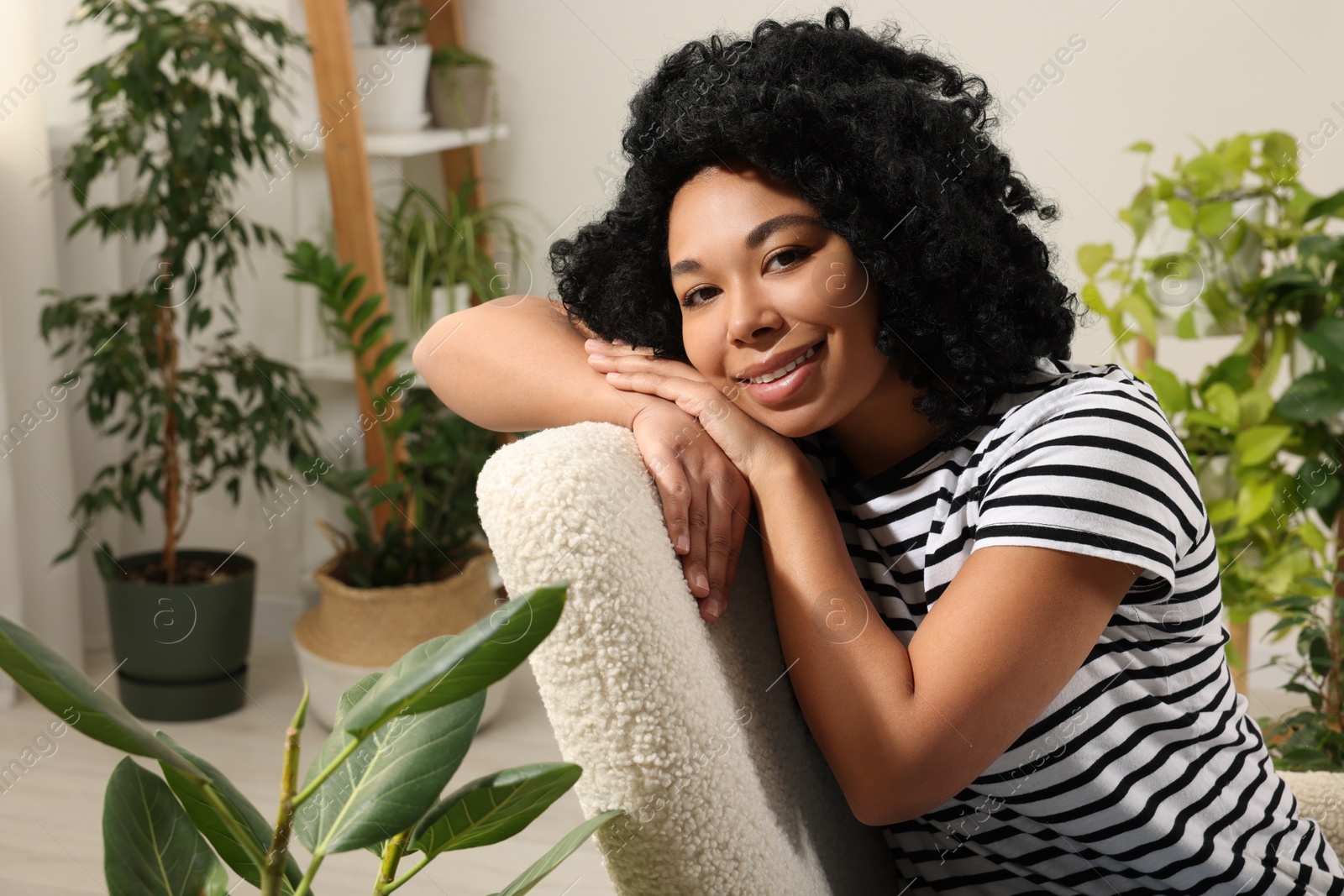 Photo of Happy woman relaxing surrounded by beautiful houseplants at home