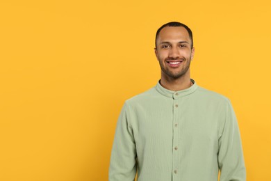 Photo of Portrait of handsome young man on orange background, space for text