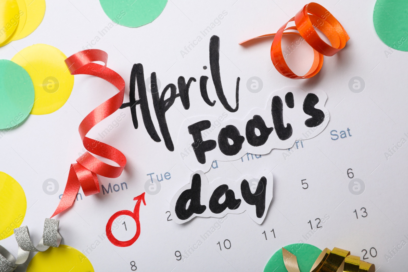 Photo of Phrase APRIL FOOL'S DAY and decor on paper calendar, flat lay