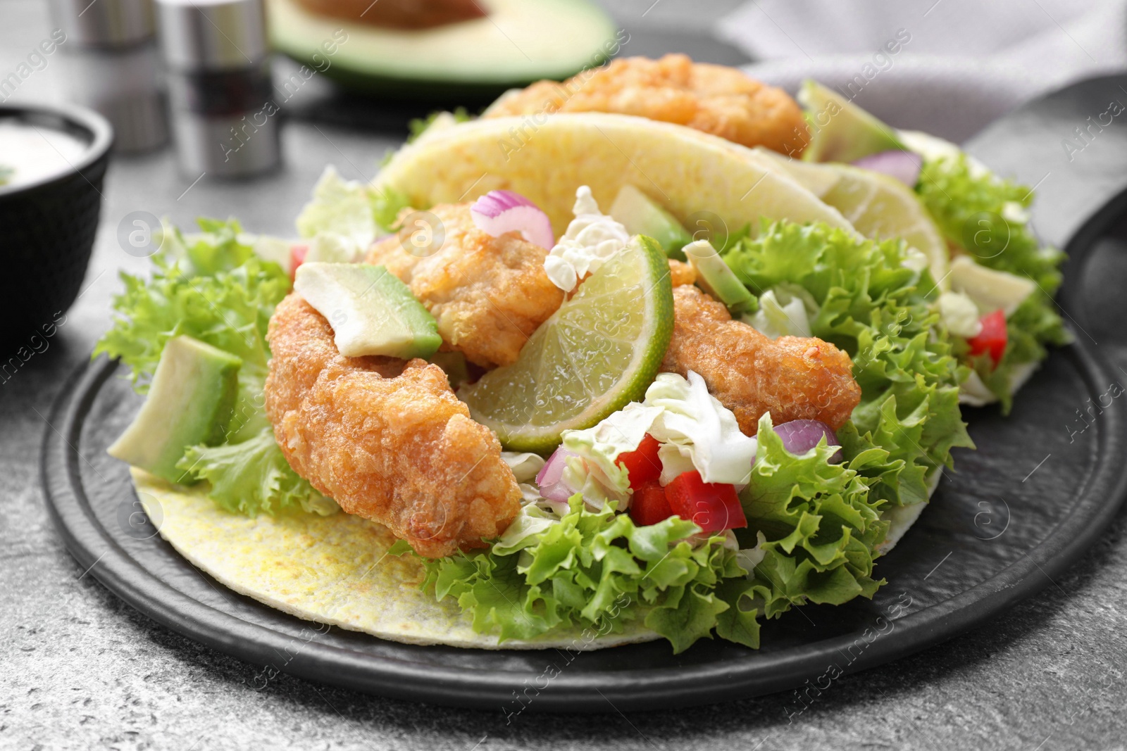 Photo of Delicious fish tacos served on grey table, closeup