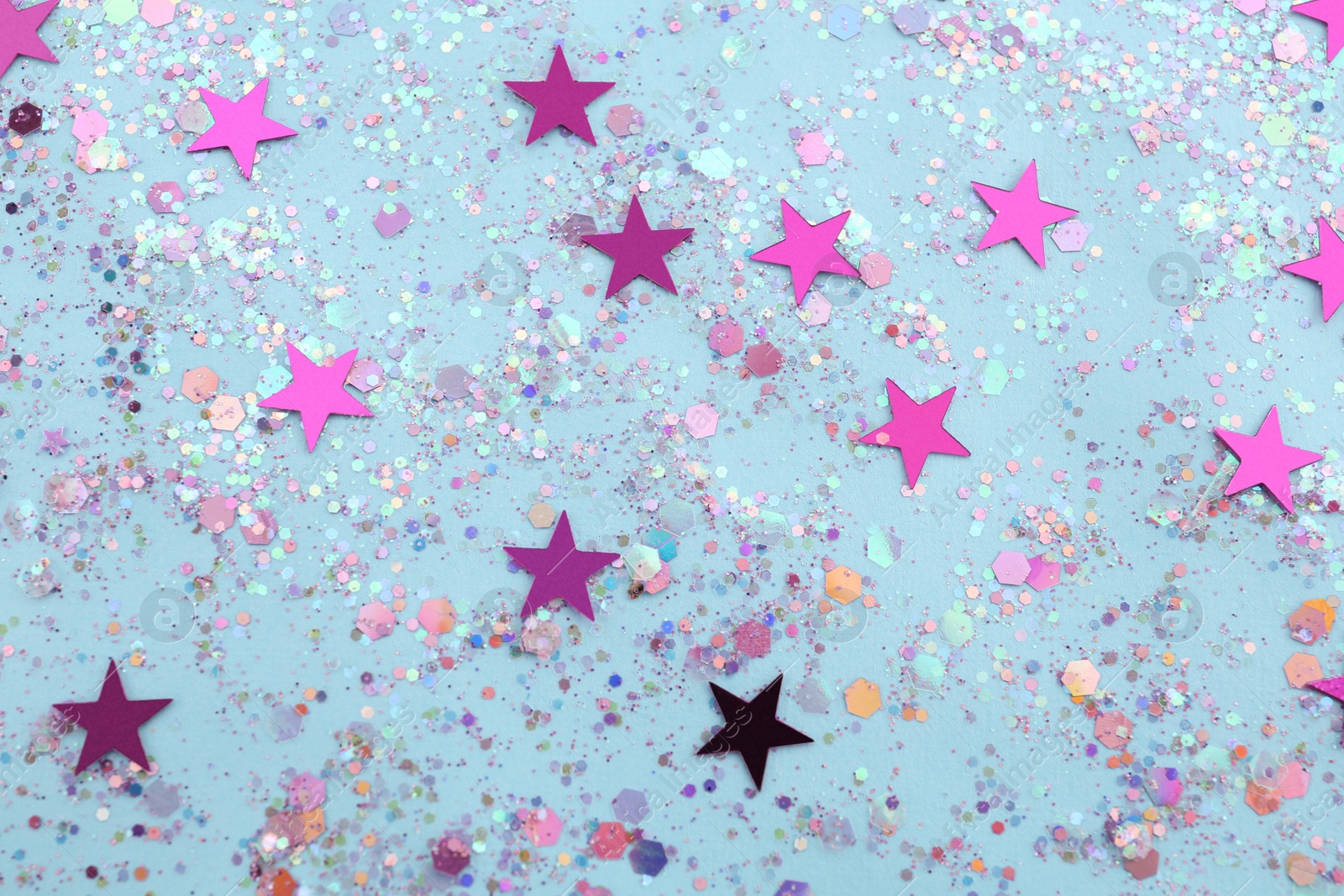 Photo of Shiny glitter on light blue background, flat lay