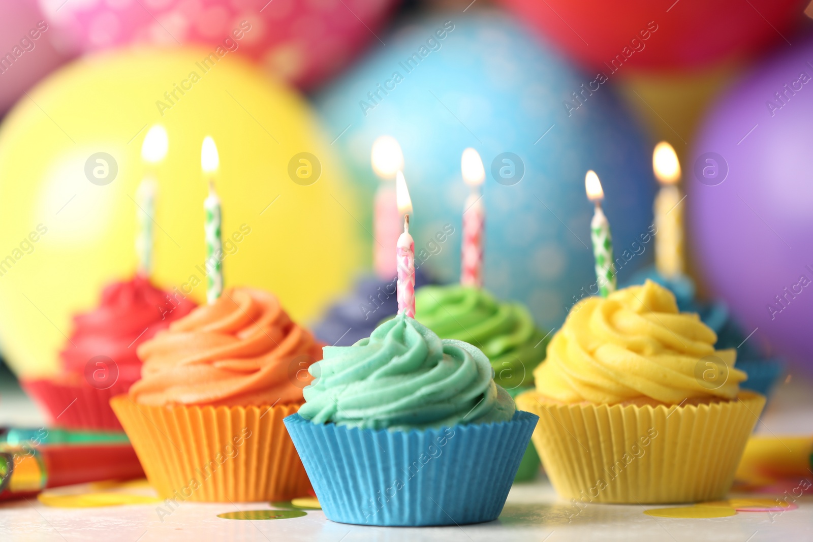 Photo of Delicious birthday cupcakes with cream and burning candles on table