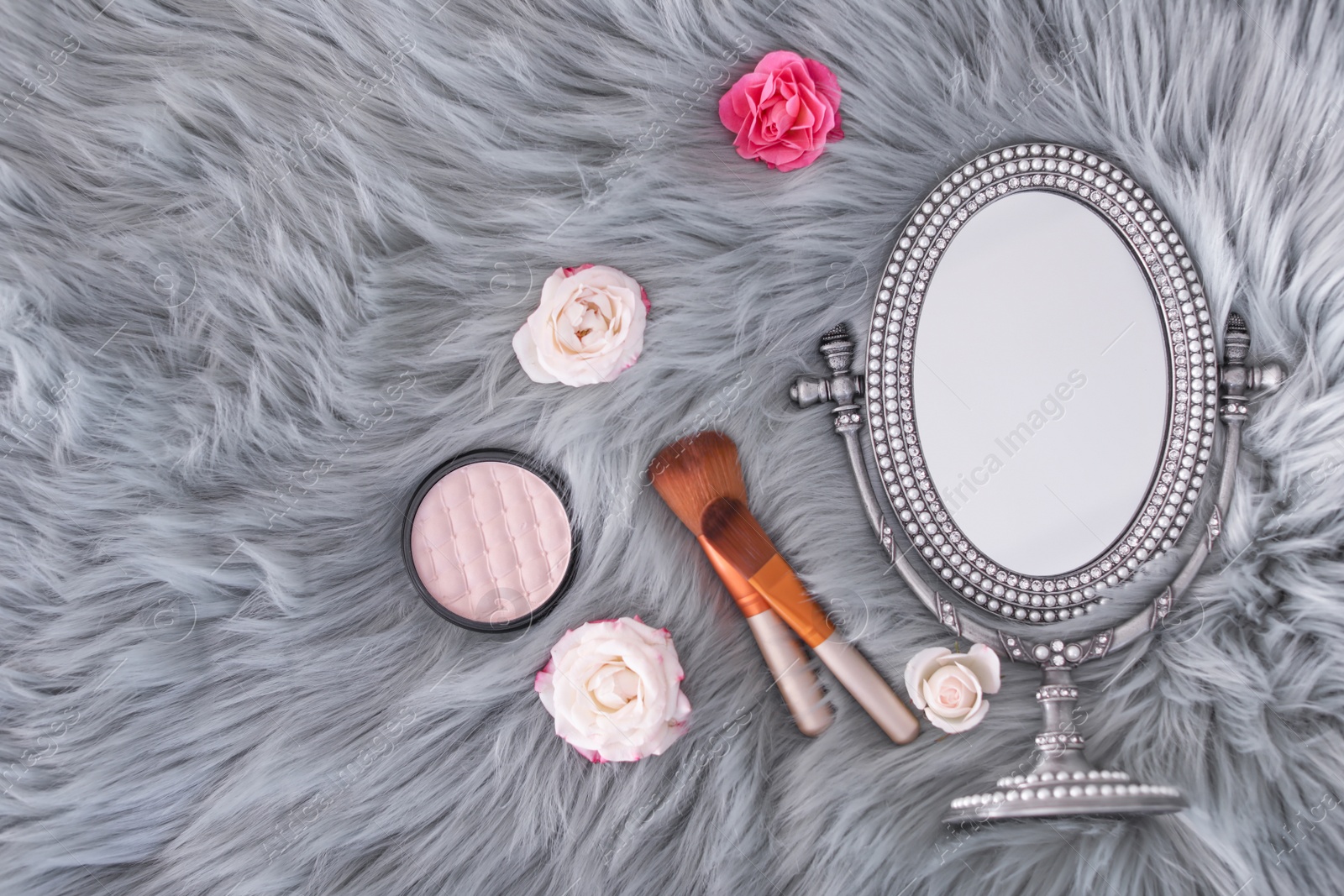 Photo of Flat lay composition with makeup brushes, roses and mirror on faux fur