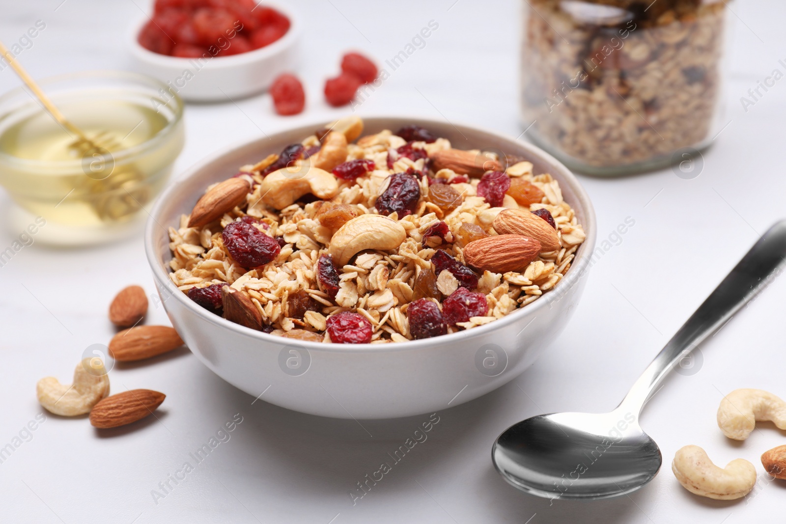 Photo of Tasty granola served with nuts and dry fruits on white marble table