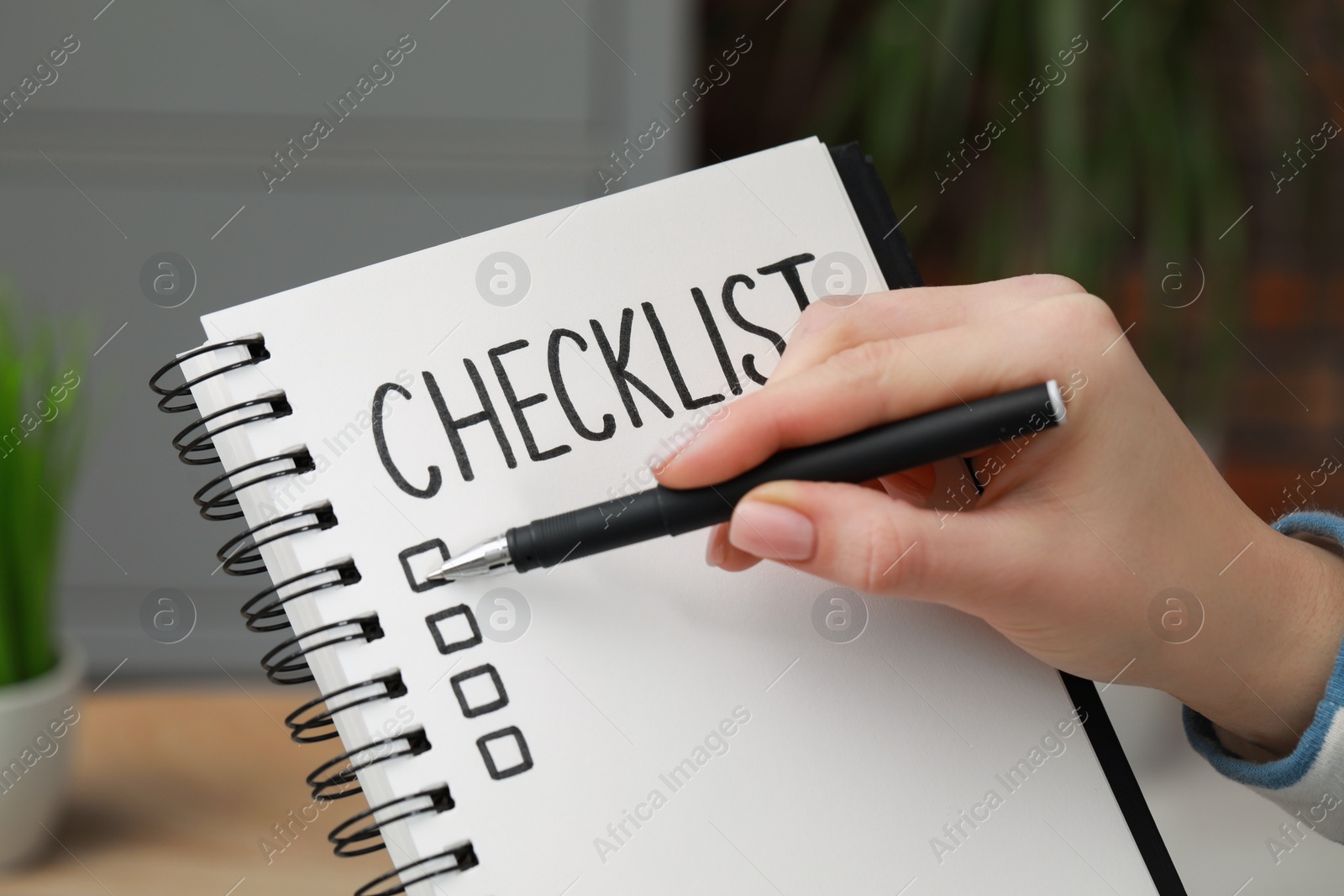 Photo of Woman filling Checklist with pen indoors, closeup