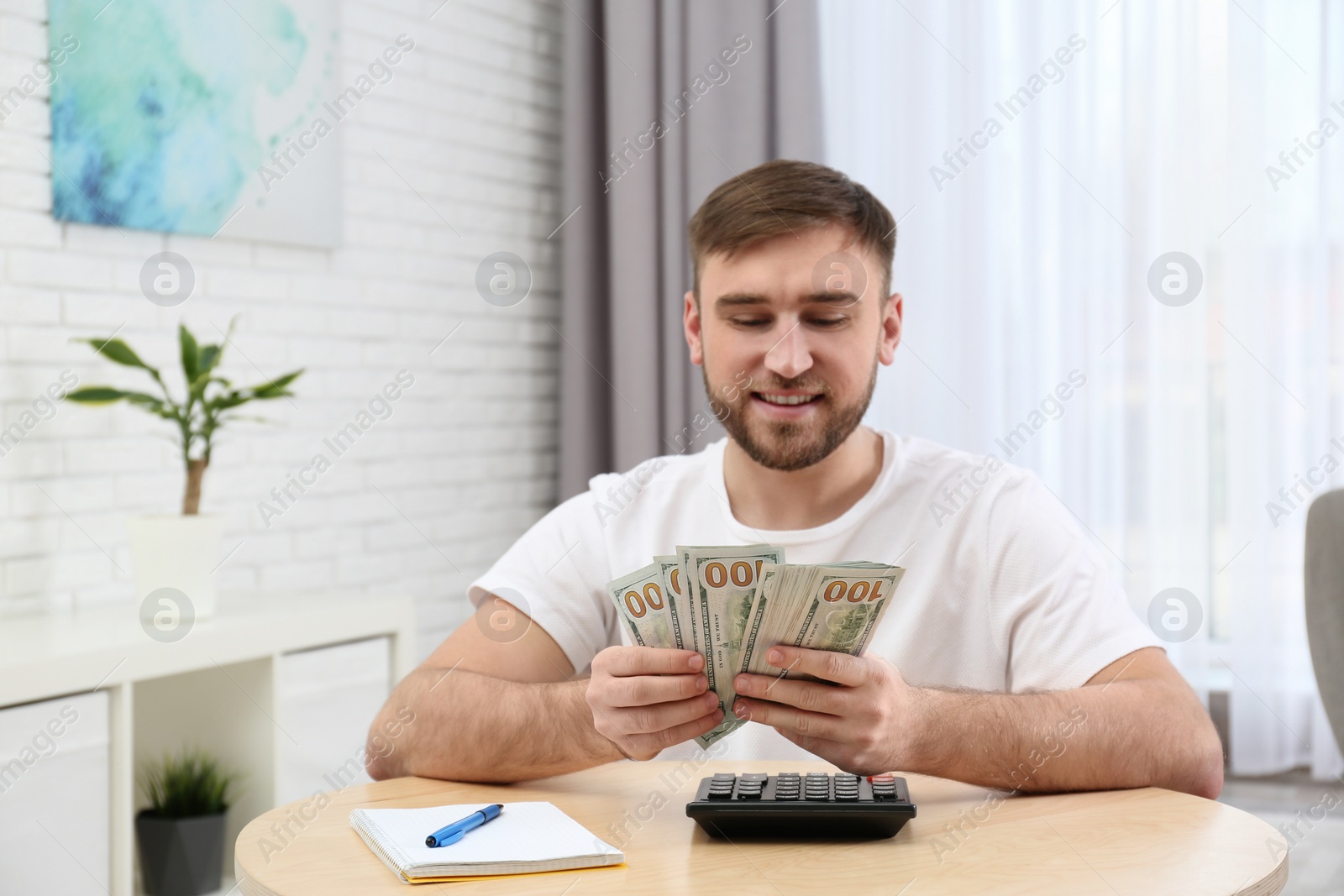 Photo of Happy young man with money at home