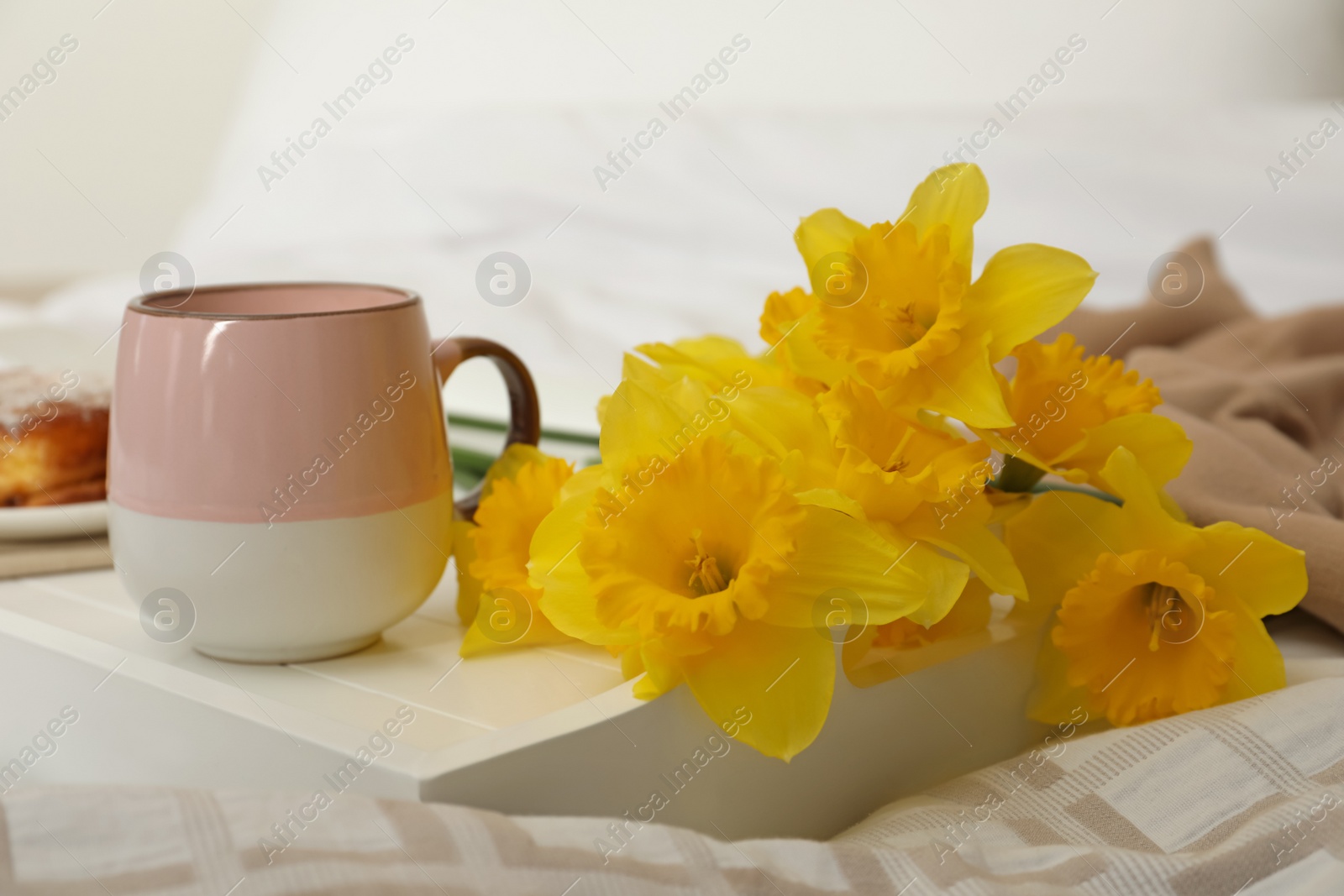 Photo of Bouquet of beautiful daffodils and coffee on bed