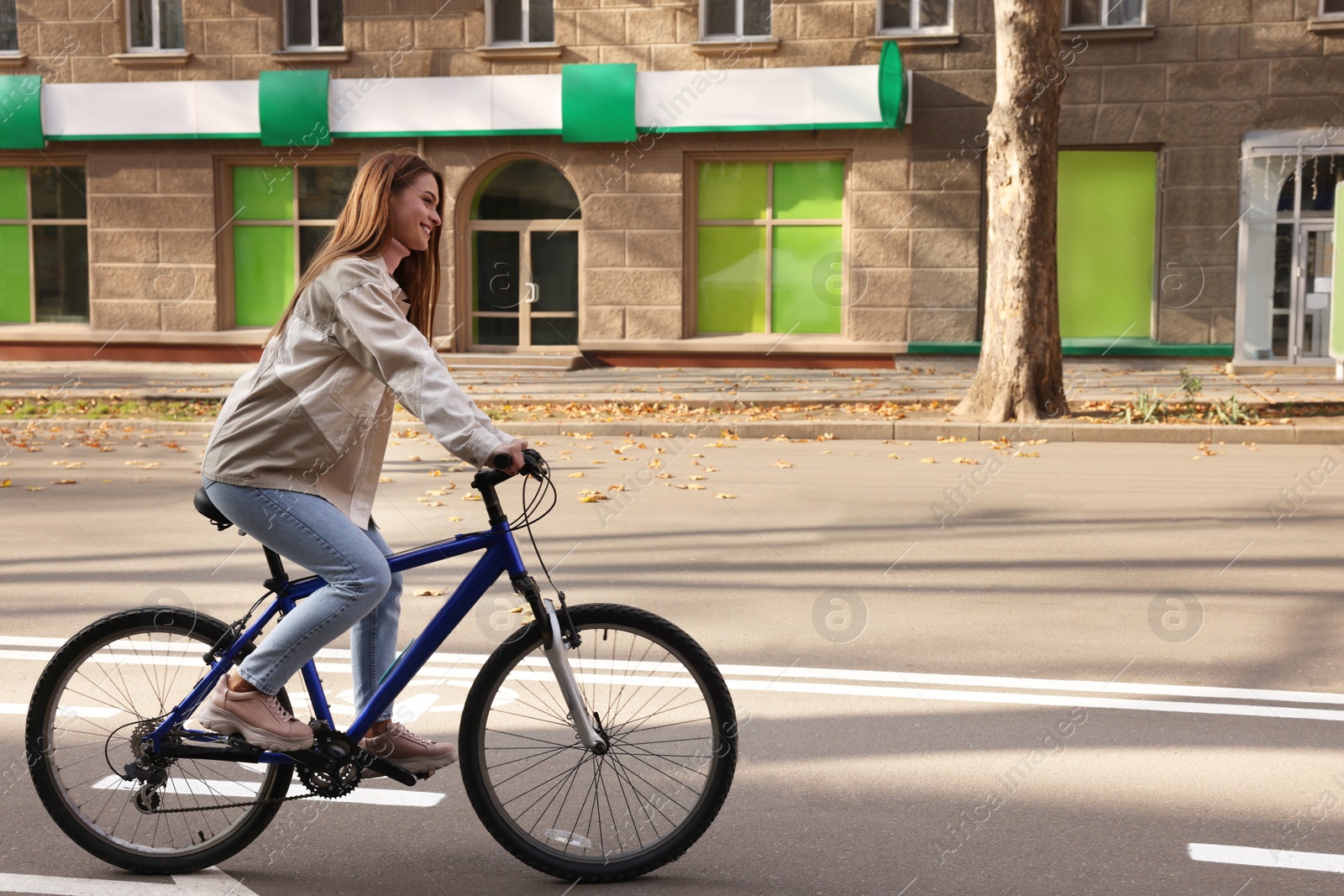 Photo of Happy beautiful woman riding bicycle on lane in city