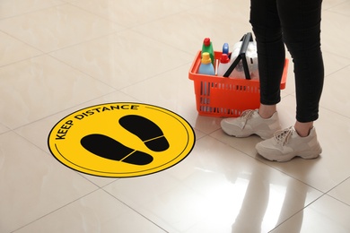 Image of Woman near sign KEEP DISTANCE in supermarket. Coronavirus pandemic