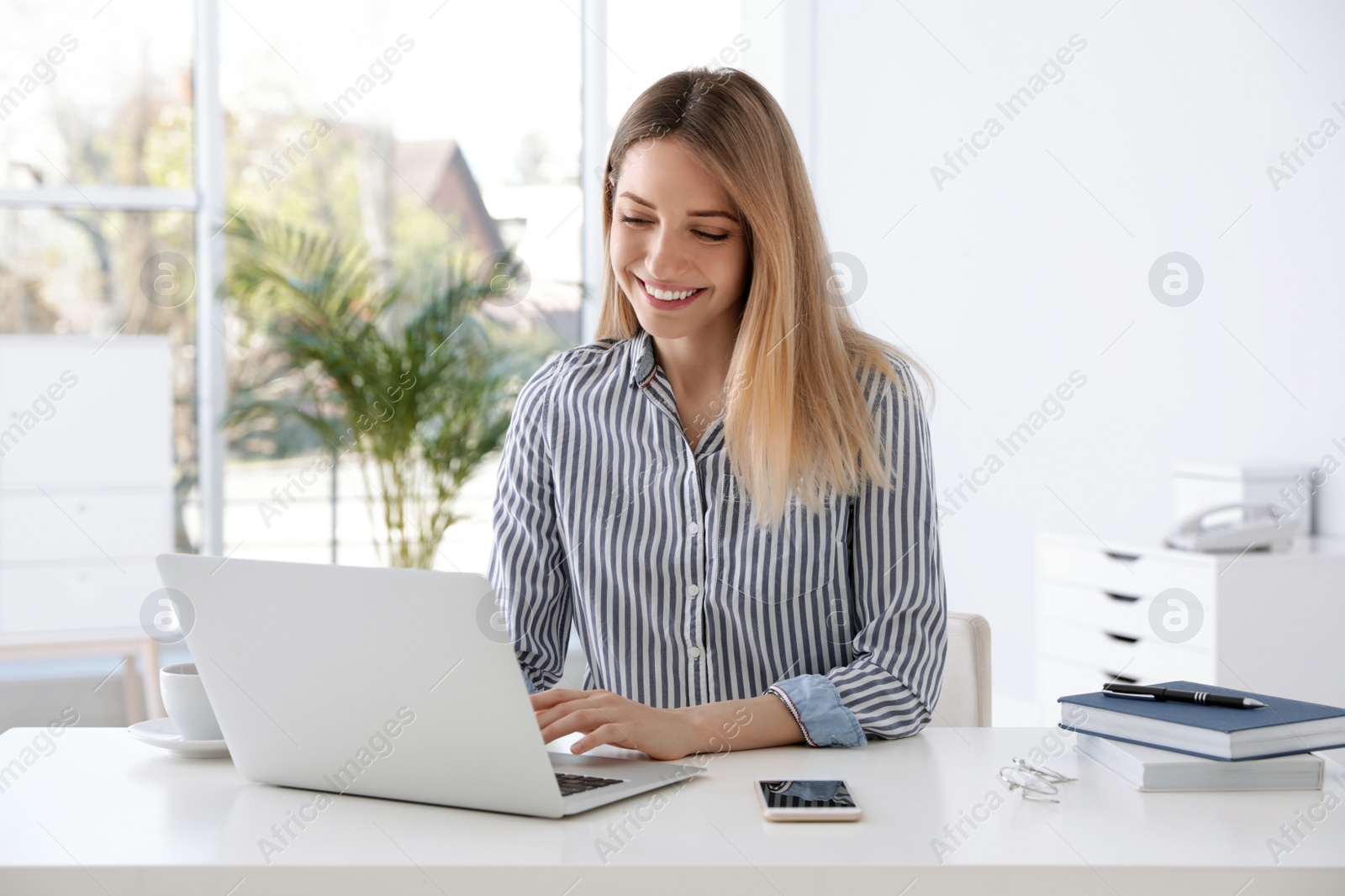 Photo of Young businesswoman using laptop at table in office