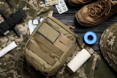 Photo of Military first aid kit and uniform on wooden table, flat lay