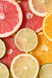 Different sliced citrus fruits as background, top view