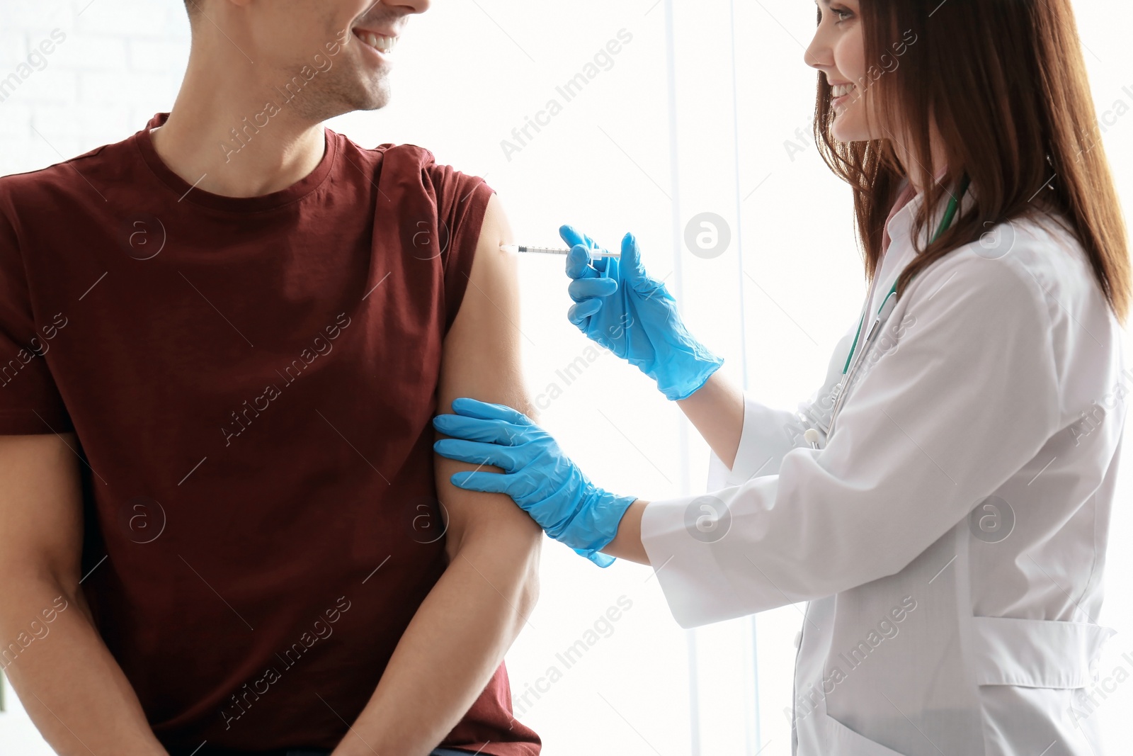 Photo of Doctor vaccinating male patient in clinic