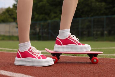 Photo of Woman with penny board wearing classic old school sneakers on sport court outdoors, closeup