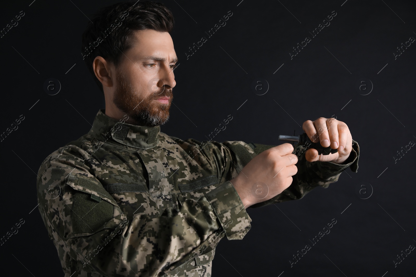 Photo of Soldier pulling safety pin out of hand grenade on black background. Military service