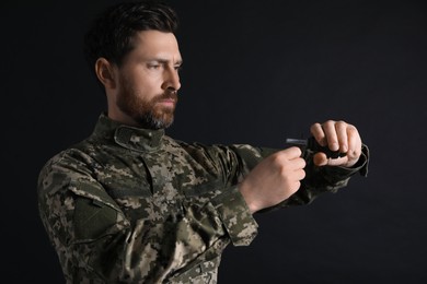 Soldier pulling safety pin out of hand grenade on black background. Military service
