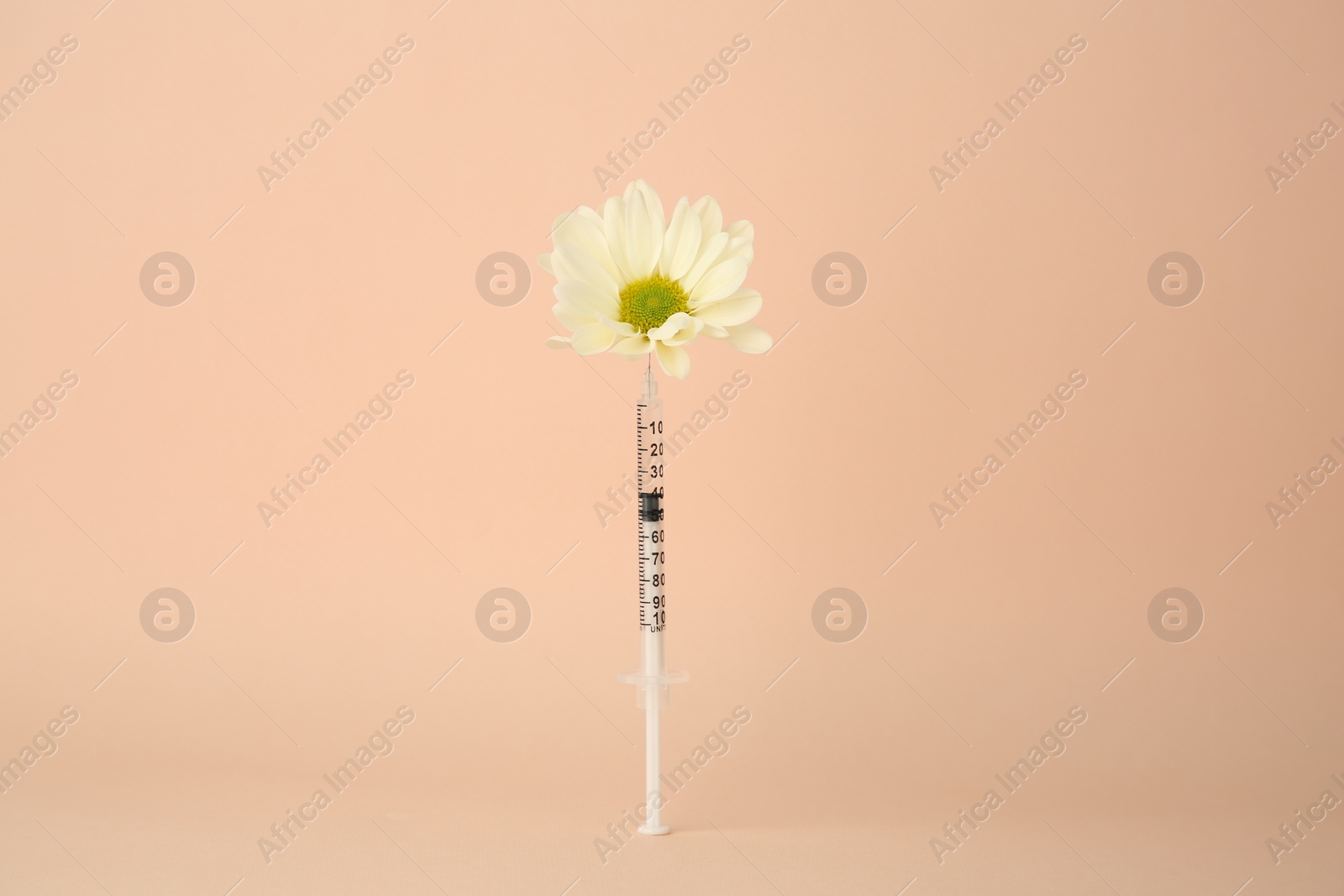 Photo of Medical syringe and chrysanthemum flower on beige background