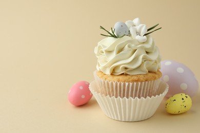 Tasty Easter cupcake with vanilla cream and candies on beige background, space for text