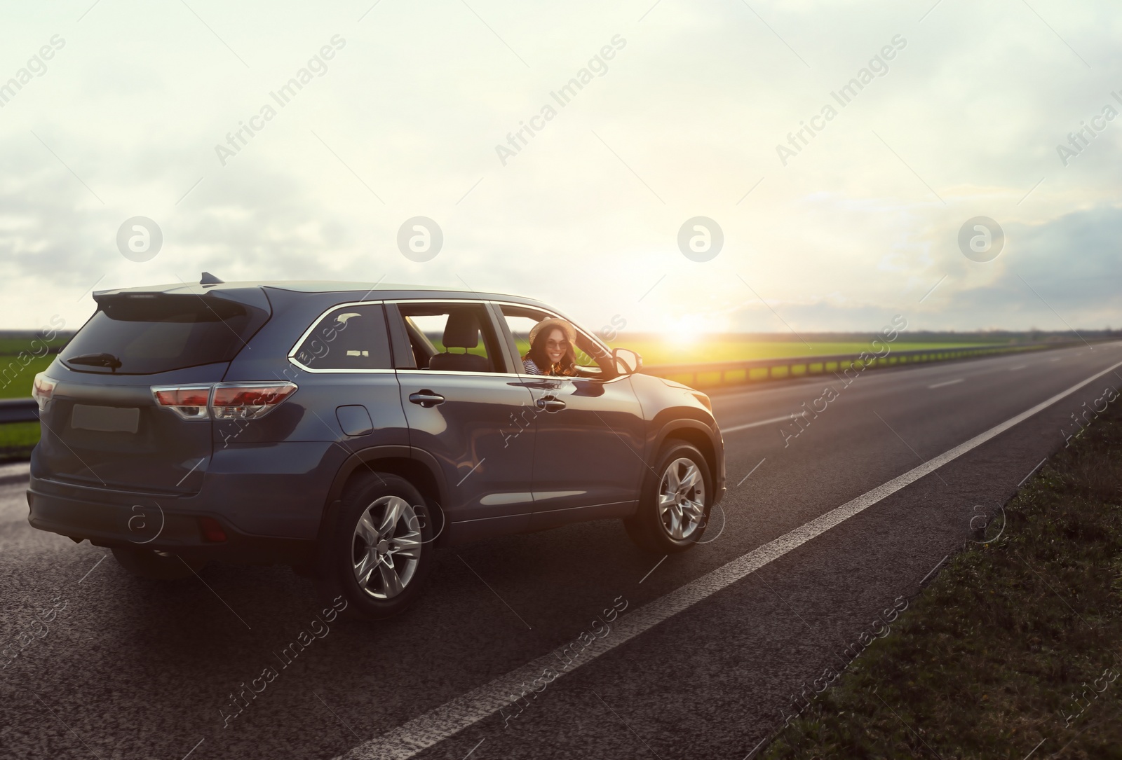 Image of Road trip. Young beautiful woman in car on asphalt highway