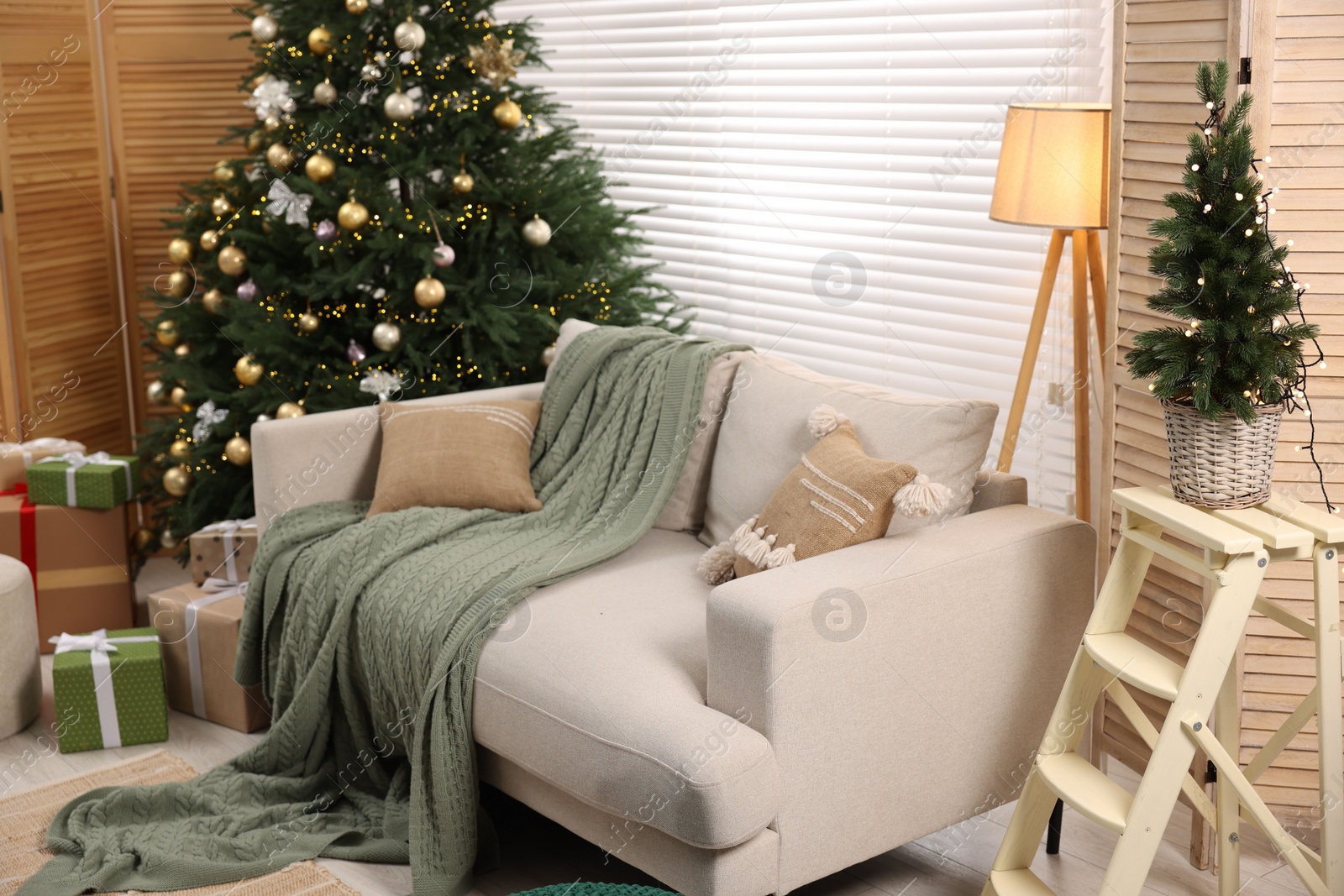 Photo of Sofa near Christmas tree in room. Festive interior design