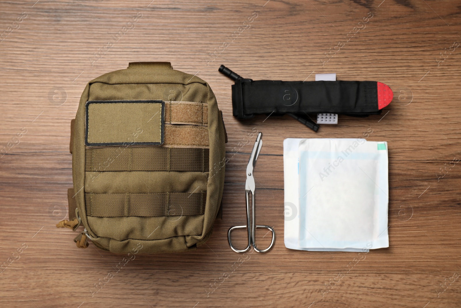 Photo of Military first aid kit on wooden table, flat lay