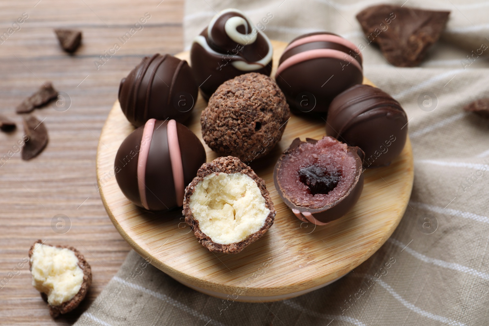 Photo of Many different delicious chocolate truffles on wooden table