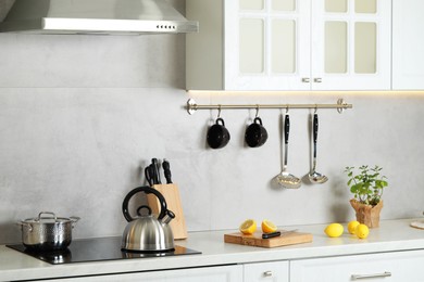 Photo of Stylish kettle with whistle on cooktop in kitchen