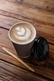 Photo of Coffee to go. Paper cup with tasty drink on wooden table
