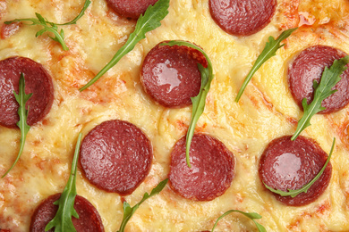 Photo of Tasty pepperoni pizza with arugula as background, top view