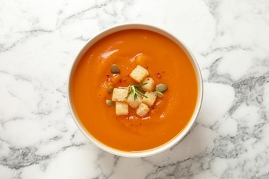 Photo of Bowl of tasty sweet potato soup on marble table, top view