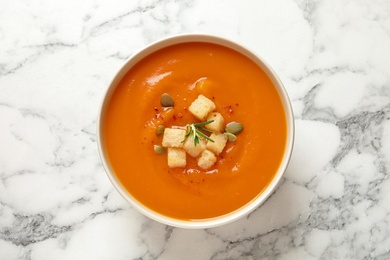 Bowl of tasty sweet potato soup on marble table, top view