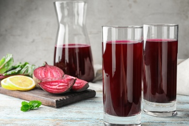 Photo of Glasses of fresh beet juice on blue wooden table. Space for text