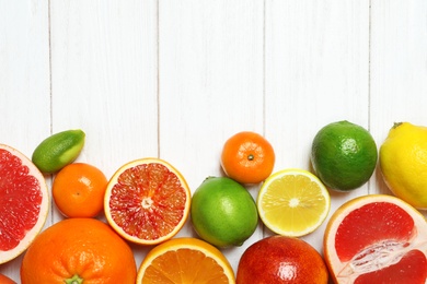 Flat lay composition with different citrus fruits and space for text on white wooden background