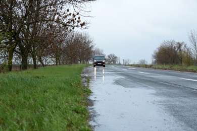 Photo of Wet suburban road with car on rainy day