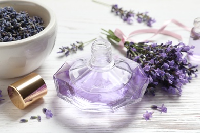 Bottle of natural perfume and lavender flowers on white wooden table. Cosmetic product