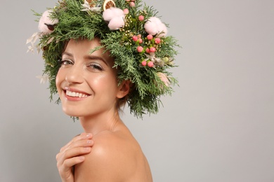 Happy young woman wearing wreath on grey background. Space for text