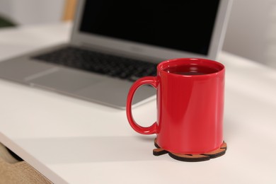 Photo of Red ceramic mug on table at workplace, space for text