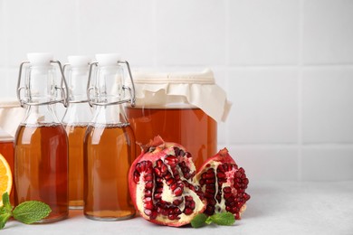 Tasty kombucha, pomegranate and mint on white table, space for text