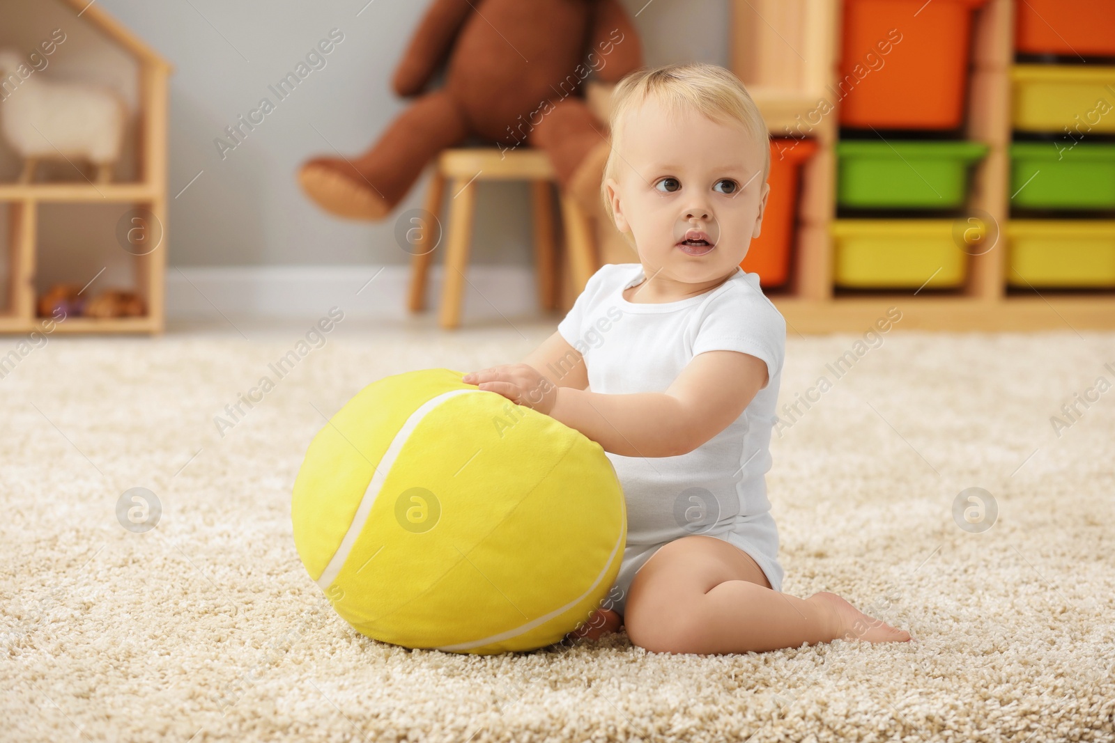 Photo of Children toys. Cute little boy playing with soft toy ball on rug at home