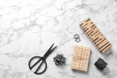 Flat lay composition with scissors and gift boxes on white marble table, space for text