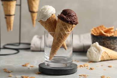 Tasty ice cream scoops in waffle cones on grey marble table, closeup