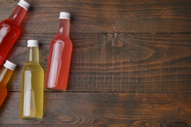 Photo of Delicious kombucha in glass bottles on wooden table, flat lay. Space for text