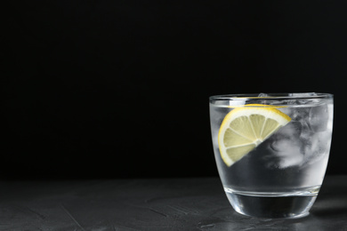 Water with ice cubes and lemon on grey table. Space for text