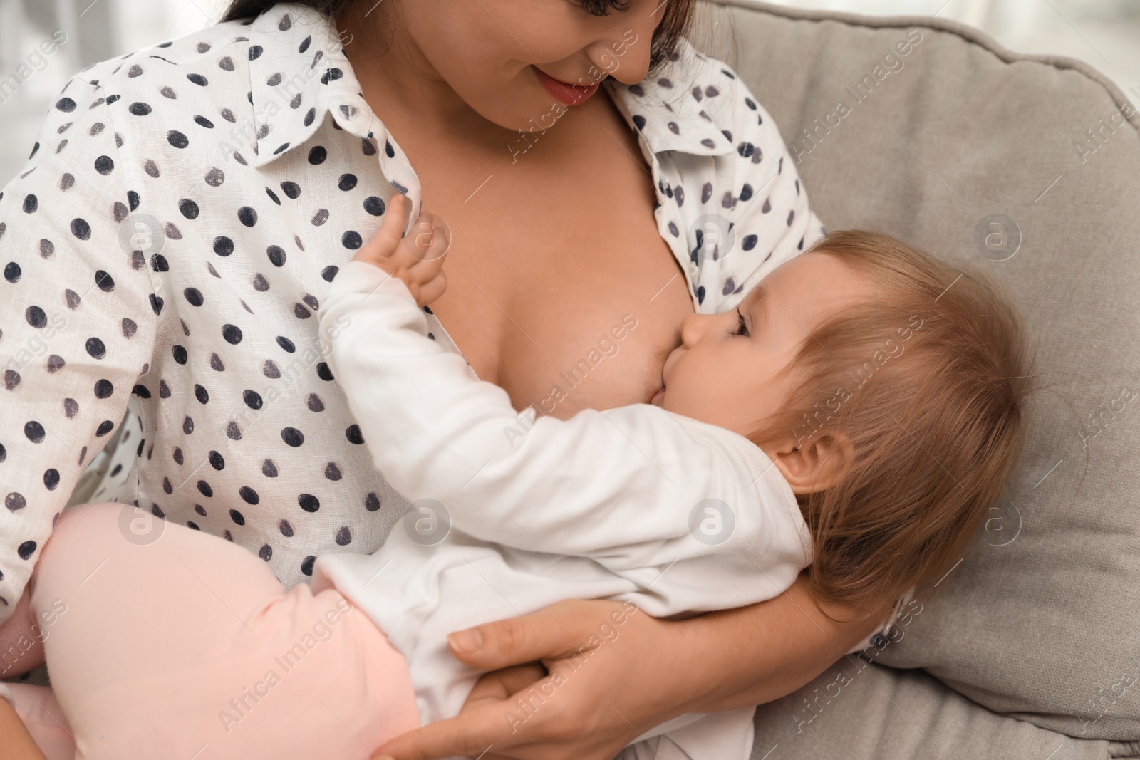 Photo of Woman breastfeeding her little baby at home, closeup